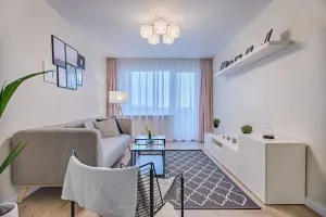 Nowoczesna łazienka z gładkimi tynkami zamiast płytek, drewnianym blatem, białą umywalką i prysznicem walk-in.