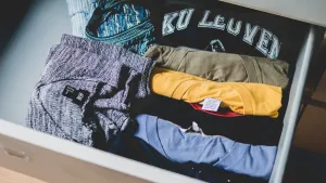 Ręka układa jasny panel podłogowy na starych płytkach w nowoczesnej łazience, pokazując szybkie odświeżenie wnętrza.